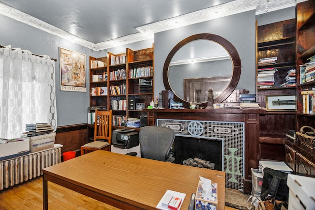 office area featuring built in features, hardwood / wood-style floors, wooden walls, and radiator