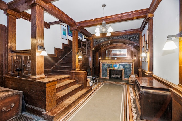 staircase with beam ceiling, decorative columns, and a chandelier