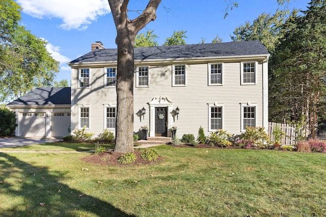 colonial-style house featuring a front yard and a garage