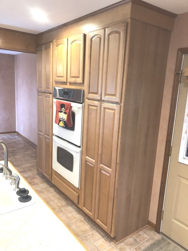 kitchen featuring sink, white double oven, and light wood-type flooring