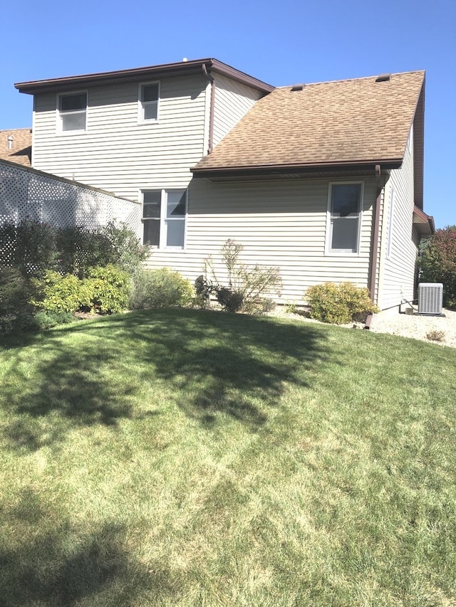 rear view of property featuring a yard and cooling unit