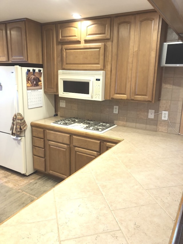 kitchen featuring white appliances, tile countertops, and backsplash