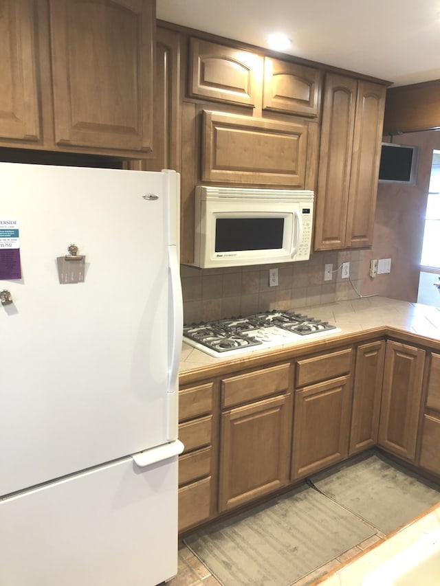 kitchen featuring decorative backsplash, tile counters, and white appliances