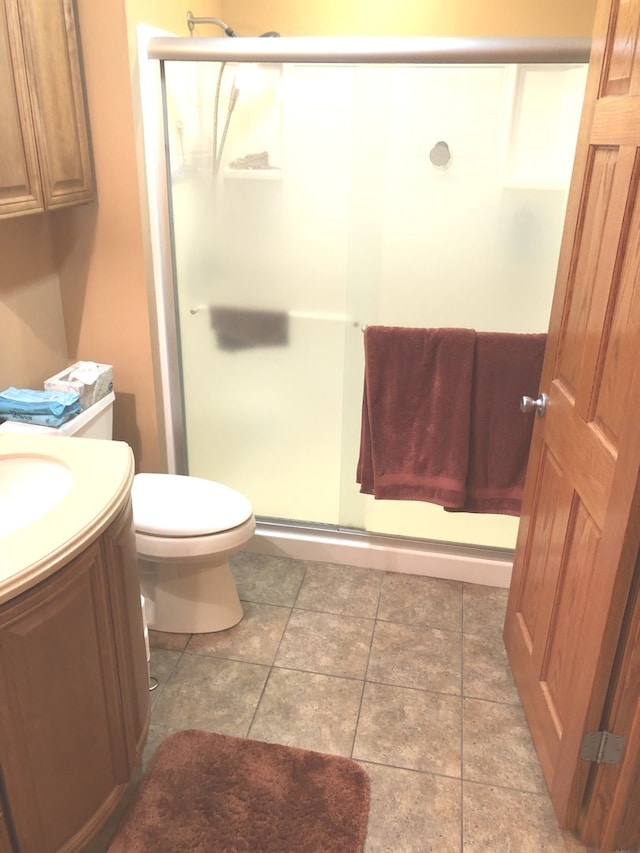 bathroom featuring vanity, tile patterned flooring, toilet, and walk in shower