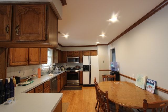 kitchen with decorative backsplash, appliances with stainless steel finishes, light wood-type flooring, crown molding, and sink