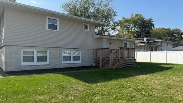 back of property featuring a wooden deck and a lawn