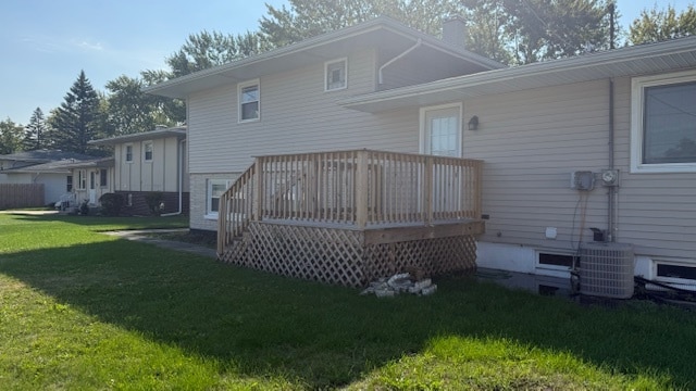 rear view of property with central air condition unit, a lawn, and a deck