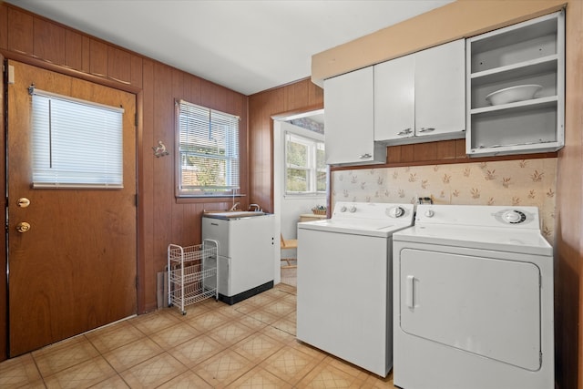 washroom featuring wooden walls, sink, independent washer and dryer, and cabinets