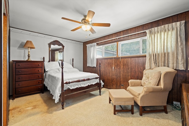 bedroom with wood walls, ceiling fan, and light colored carpet