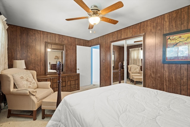 bedroom with a closet, wood walls, ceiling fan, and light colored carpet