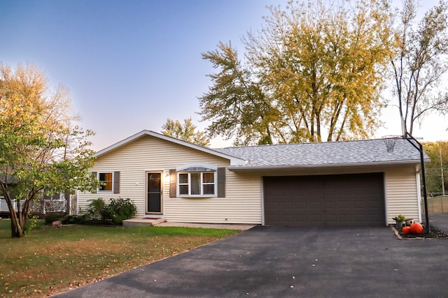 ranch-style home featuring a garage and a lawn