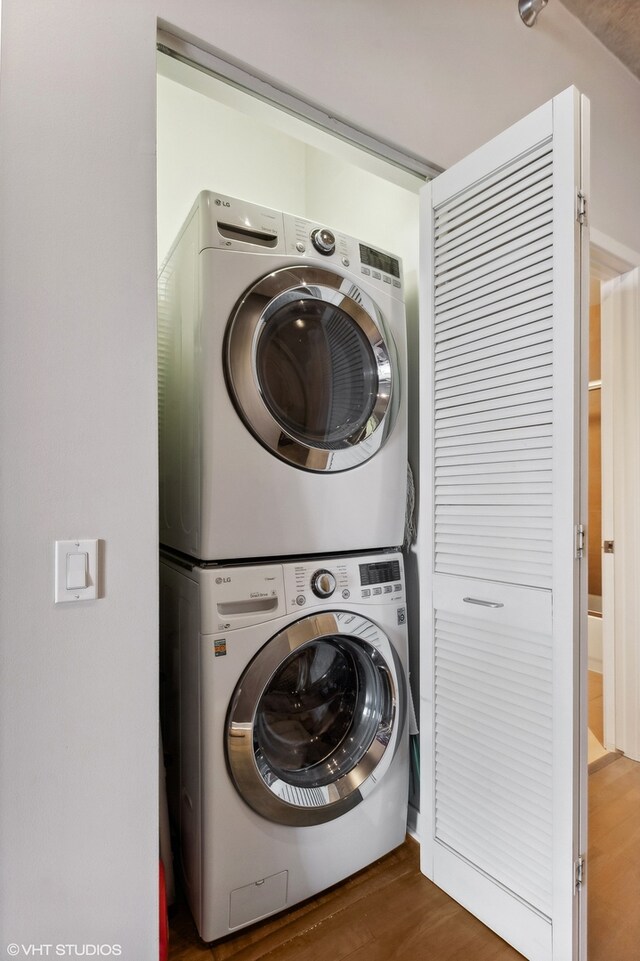 clothes washing area with stacked washer / drying machine and dark hardwood / wood-style flooring