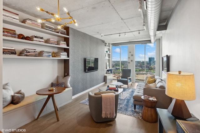 living room with rail lighting, a chandelier, expansive windows, and hardwood / wood-style flooring