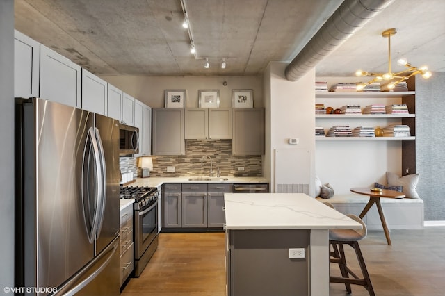 kitchen with hanging light fixtures, sink, gray cabinetry, appliances with stainless steel finishes, and light wood-type flooring