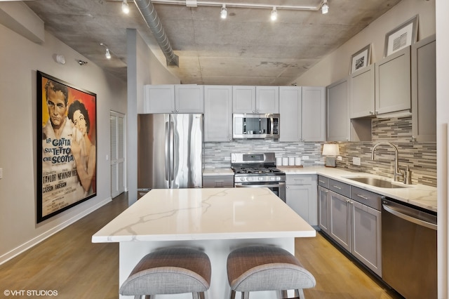 kitchen with stainless steel appliances, light hardwood / wood-style floors, a center island, and sink