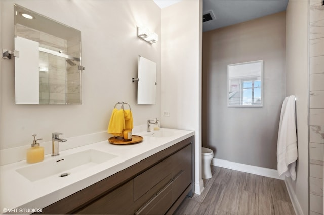 bathroom featuring hardwood / wood-style flooring, a shower with door, vanity, and toilet