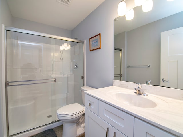 bathroom with a shower with door, hardwood / wood-style floors, vanity, and toilet