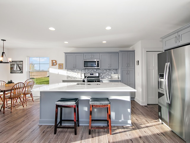 kitchen with pendant lighting, wood-type flooring, gray cabinets, and appliances with stainless steel finishes