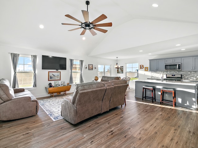 living room featuring ceiling fan with notable chandelier, dark hardwood / wood-style flooring, and high vaulted ceiling