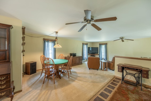 carpeted dining area with ceiling fan