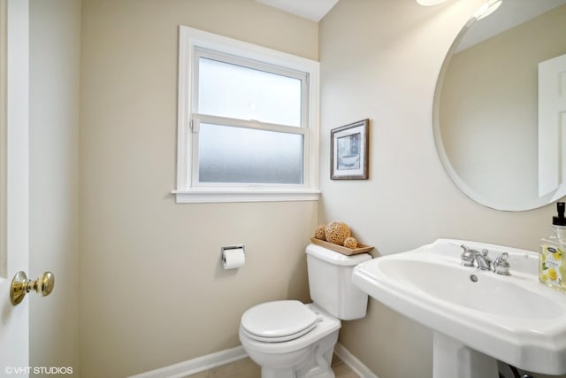 bathroom with toilet, baseboards, and a sink