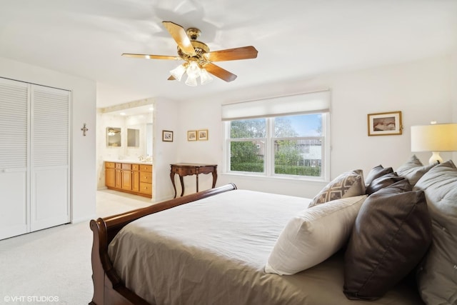 bedroom with a ceiling fan, ensuite bathroom, and light carpet