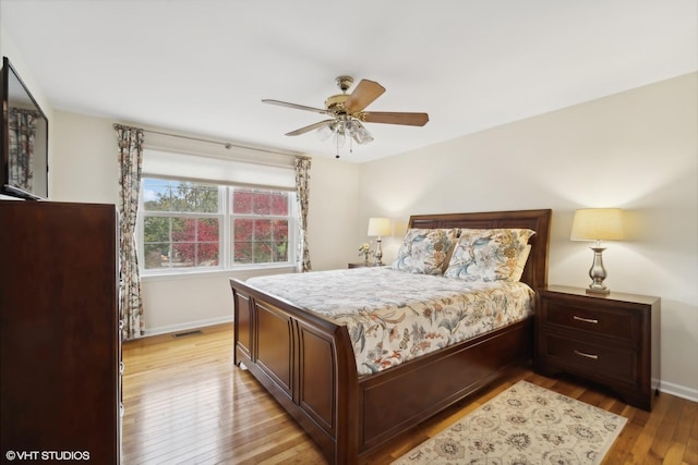 bedroom with baseboards, visible vents, light wood finished floors, and ceiling fan