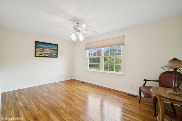 living area featuring a ceiling fan, visible vents, baseboards, and light wood-type flooring