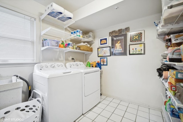 washroom with baseboards, laundry area, light tile patterned flooring, independent washer and dryer, and a sink