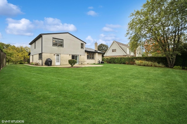 back of house with a patio area, a lawn, a chimney, and fence