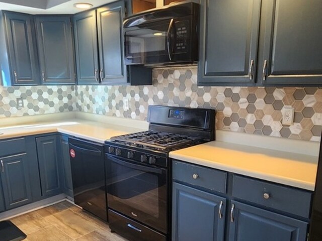 kitchen with blue cabinetry, black appliances, and decorative backsplash