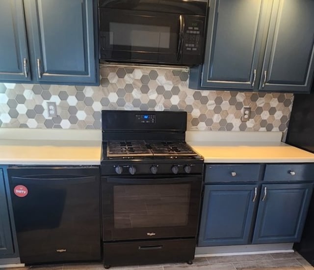 kitchen with blue cabinetry, black appliances, and decorative backsplash