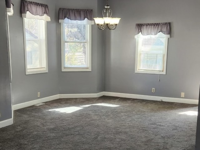 empty room with a chandelier, carpet flooring, and a healthy amount of sunlight