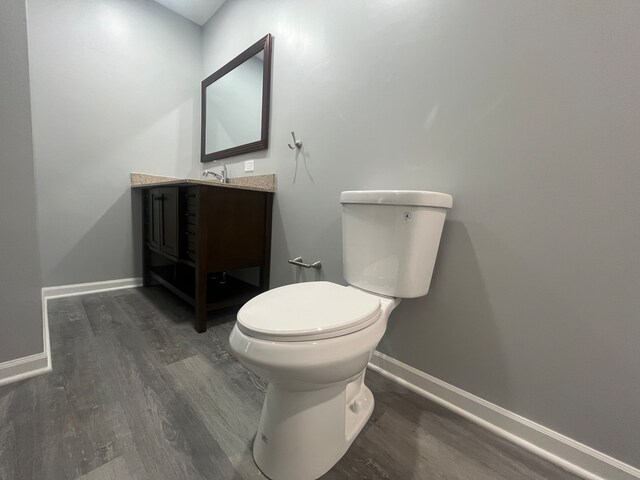 bathroom with hardwood / wood-style floors, vanity, and toilet