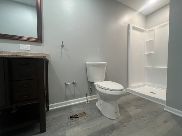 bathroom featuring a shower, hardwood / wood-style floors, vanity, and toilet