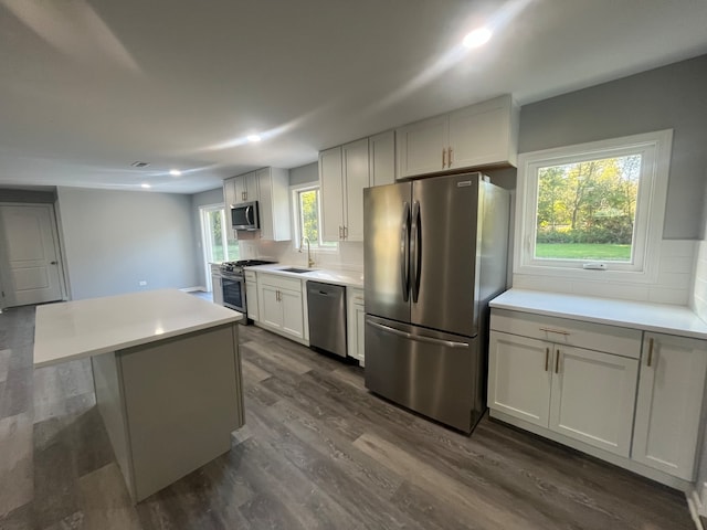 kitchen featuring white cabinets, stainless steel appliances, dark hardwood / wood-style floors, a center island, and decorative backsplash