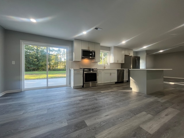 kitchen with appliances with stainless steel finishes, plenty of natural light, dark wood-type flooring, and white cabinetry