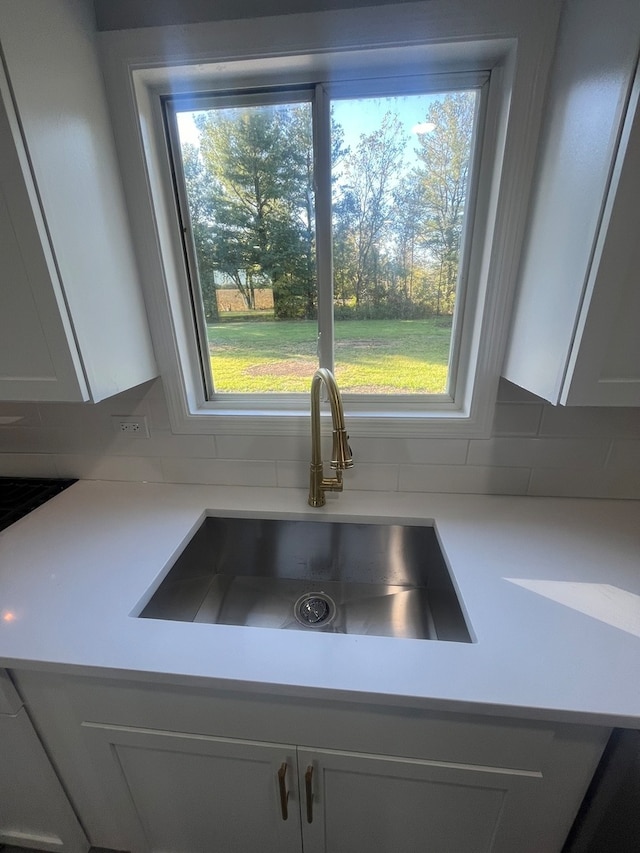 kitchen with backsplash, sink, and white cabinetry