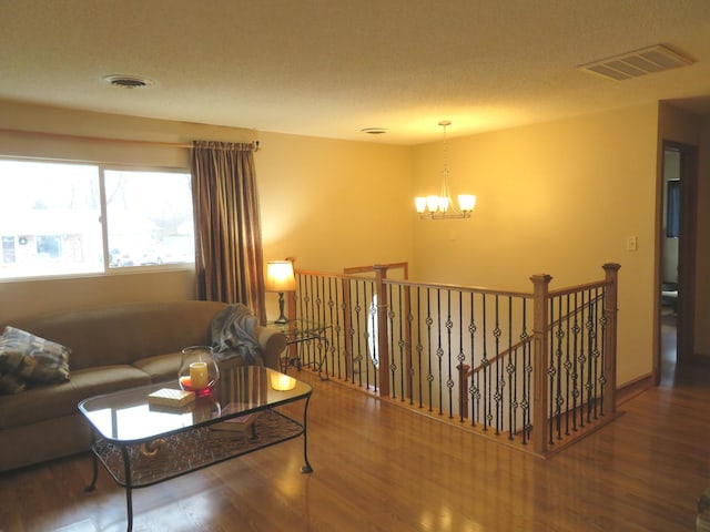 living room with a textured ceiling, a notable chandelier, and dark wood-type flooring