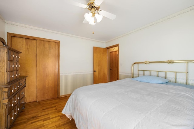 bedroom featuring a closet, hardwood / wood-style floors, ornamental molding, and ceiling fan