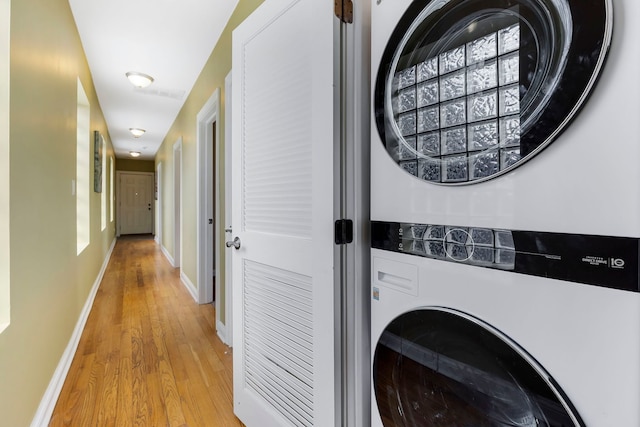 laundry room featuring light hardwood / wood-style flooring and stacked washer and clothes dryer