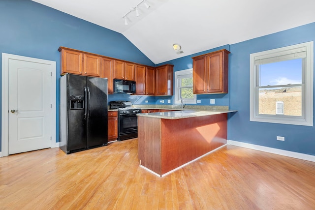 kitchen with lofted ceiling, black appliances, kitchen peninsula, and light wood-type flooring