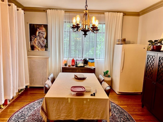 dining space featuring a notable chandelier, ornamental molding, and dark hardwood / wood-style floors