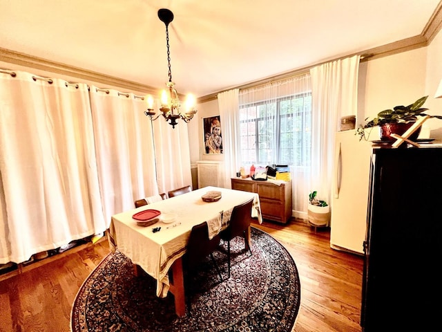 dining space with ornamental molding, wood-type flooring, and a chandelier