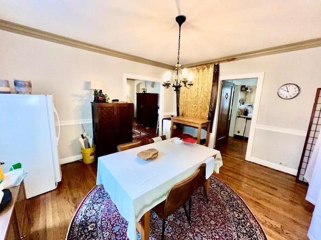 dining room with ornamental molding, dark hardwood / wood-style floors, and a notable chandelier