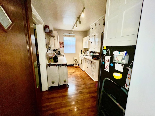 kitchen with white cabinetry, white appliances, track lighting, and dark wood-type flooring