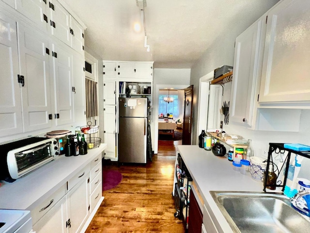 kitchen featuring dark hardwood / wood-style floors, white cabinetry, sink, stainless steel fridge, and track lighting