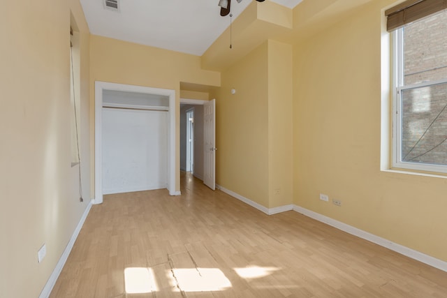 unfurnished bedroom with light wood-type flooring, multiple windows, and a closet