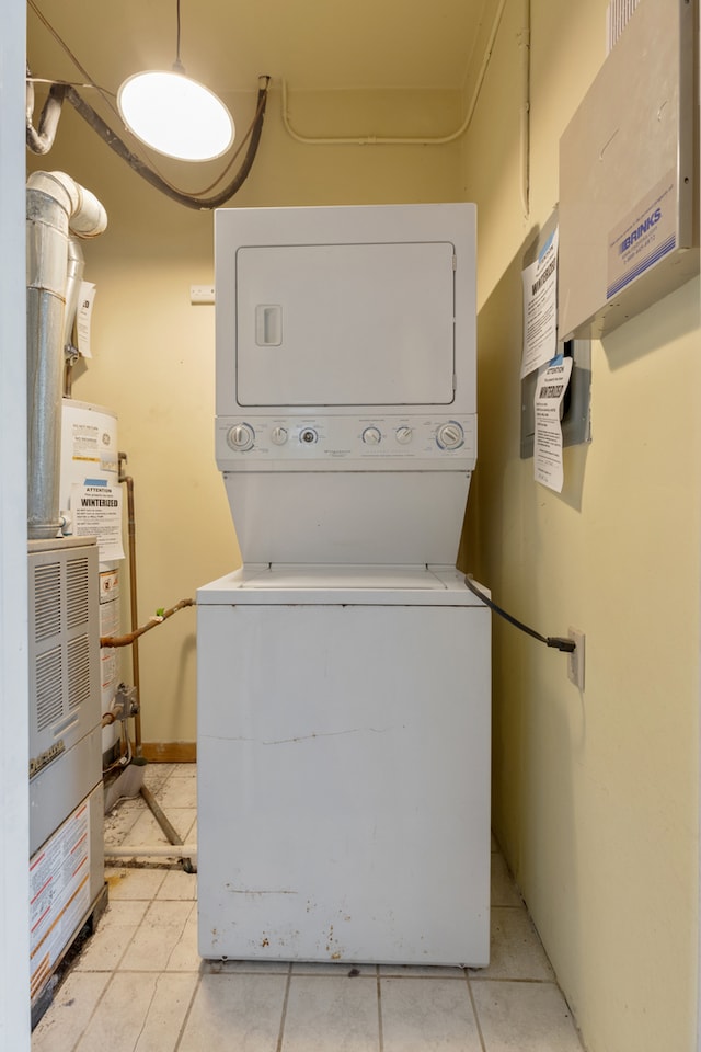 laundry room featuring light tile patterned floors and stacked washer / drying machine