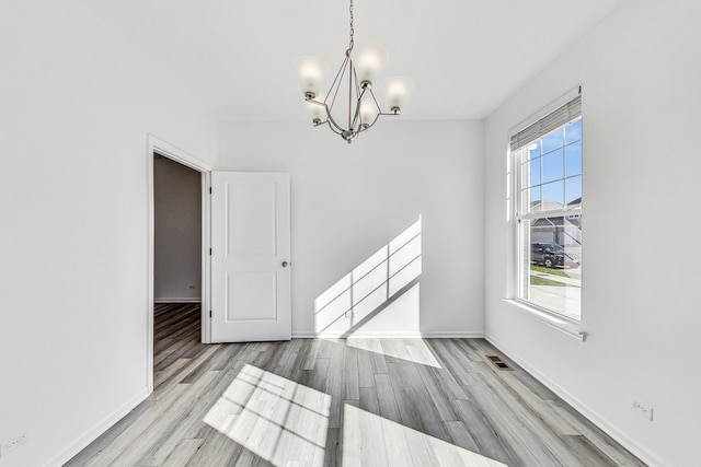 unfurnished dining area featuring a chandelier and light wood-type flooring